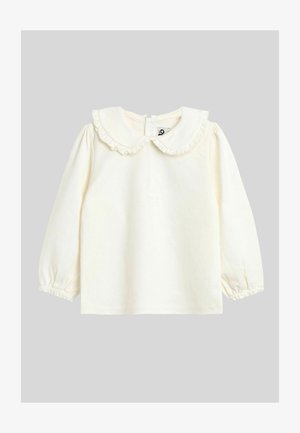 Hosszú ujjú krémszínű felső fodros gallérral és gombos záródással a hátsó részen. Puha anyag, ráncolt mandzsettákkal és sima textúrával.