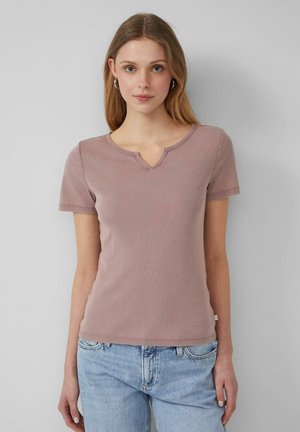 T-shirt rose clair à manches courtes et col en V, fabriqué dans un tissu texturé. Associé à un jean bleu clair.