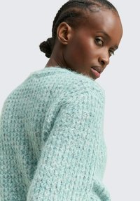 Lichtblauwe, getextureerde gebreide trui met een loose fit en een ronde halslijn. Heeft zichtbare stiksels en een zachte, fuzzy stof.