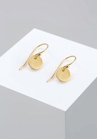 Auksinio atspalvio auskarai su apvaliais, tekstūruotais diskais, kabančiais ant ilgesnių kabliukų, su mažais raudonais akcentais prie užsegimo.