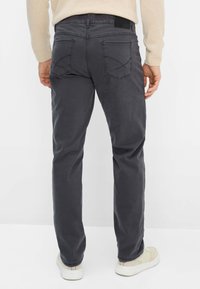 Graue Baumwollhose mit geradem Bein, ausgestattet mit Gesäßtaschen mit dekorativer Naht und einem schwarzen Taillenetikett. Legeres Design.