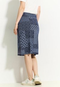 Námořnická modrá sukně s komplikovanými světle modrými geometrickými a květinovými vzory, ke kolenům, s bočním rozparkem a elastickým pasem.