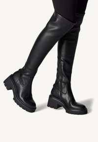 Czarne skórzane kozaki za kolano z grubym, kwadratowym obcasem i teksturowaną podeszwą. Posiadają boczny zamek błyskawiczny i eleganckie, gładkie wykończenie.