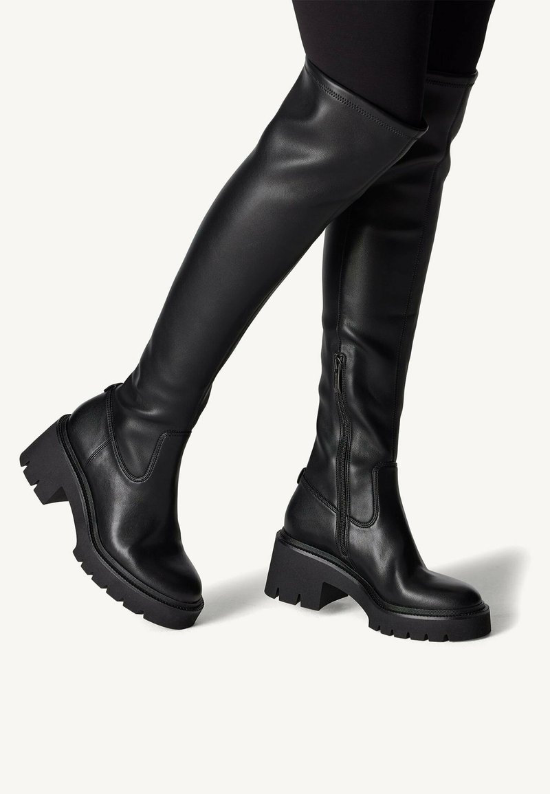 Czarne skórzane kozaki za kolano z grubym, kwadratowym obcasem i teksturowaną podeszwą. Posiadają boczny zamek błyskawiczny i eleganckie, gładkie wykończenie.