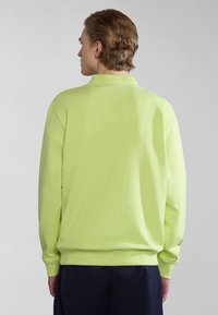 Sudadera verde neón de manga larga, con puños acanalados, cuello redondo y un ajuste relajado, mostrada desde la parte de atrás contra un fondo neutro.