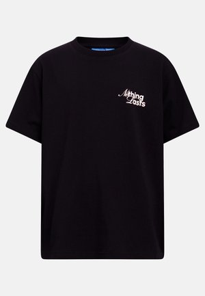 Svart T-skjorte med korte ermer og hvit tekst "Nothing Lasts" på venstre bryst, vist på ensfarget lys grå bakgrunn.