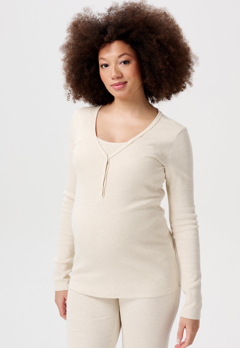 Beige, geribbelde lange mouwen top met een V-hals en decoratieve naad. Gepaarde met bijpassende beige broek, ontworpen voor comfort tijdens de zwangerschap.