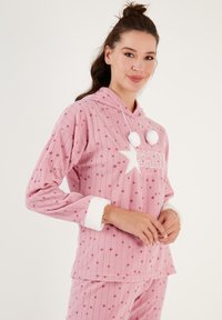 Conjunto de ropa de lounge de felpa rosa que incluye capucha, diseño de rayas texturizadas, patrón de estrellas, puños blancos esponjosos y acentos de pompones.
