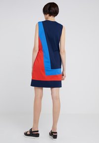 Sleeveless dress featuring a color-block design with navy, red, and blue sections. Made of smooth fabric, it has a back zipper closure.