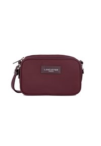 Borsa a tracolla compatta color burgundy con chiusura a zip, tracolla regolabile e patch del logo Lancaster Paris sul davanti.