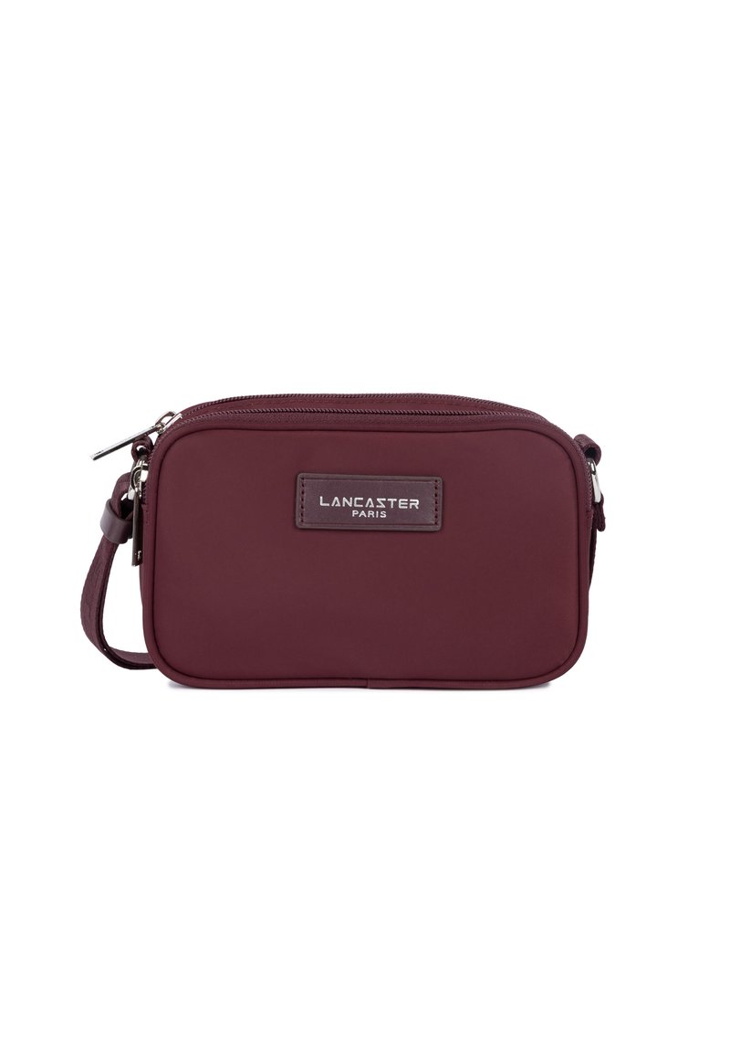 Borsa a tracolla compatta color burgundy con chiusura a zip, tracolla regolabile e patch del logo Lancaster Paris sul davanti.