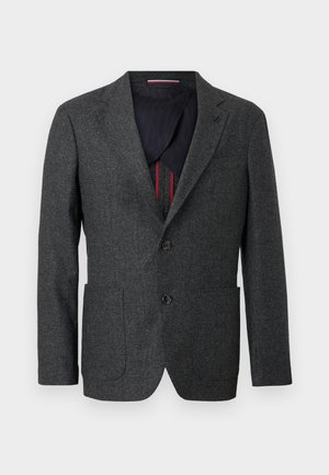 Blazer de tweed gris oscuro con solapa con muesca, dos bolsillos delanteros y dos botones. El interior presenta un forro azul marino en contraste y detalles en rojo.