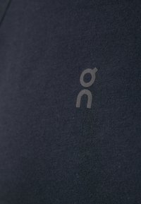 Dark navy short-sleeve shirt made of cotton, features a small, grey logo on the front side with a smooth texture.