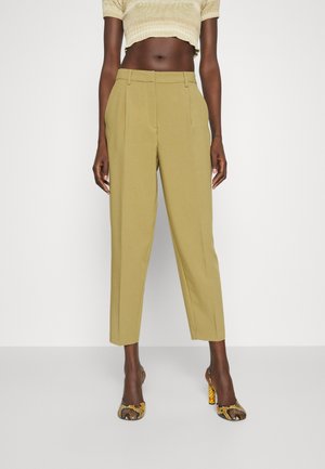 Pantalons taillés en kaki avec une taille haute, un devant plat et des jambes légèrement fuselées. Associés à des chaussures à talons hauts à motifs.