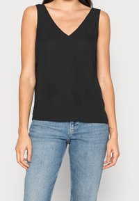 Top senza maniche nero con scollatura a V, realizzato in tessuto liscio, caratterizzato da un taglio rilassato e uno stile minimalista. Abbinate a jeans blu.