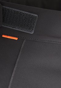 Fascia elastica sportiva nera con una toppa in Velcro testurizzata, cuciture di accento arancioni e un tessuto liscio. Presenta cuciture precise lungo le cuciture.