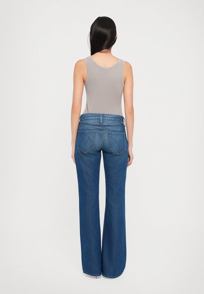 Hoge taille wijde jeans in donkerblauwe denim met een klassiek vijf-pocket ontwerp en contraststiksels, gecombineerd met een grijze geribde tanktop.