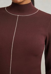 Csíkozott, bordó turtleneck felső kontrasztos fehér varrással a középen. Puha tapintás, testhezálló fazon.