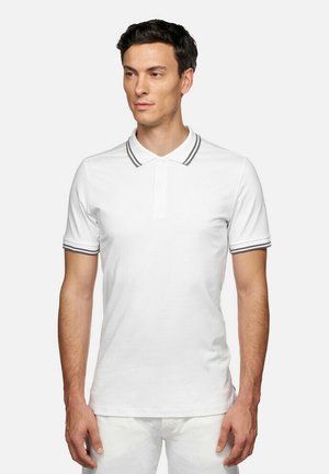 Polo shirt bianco con una patta a due bottoni e accenti grigi a righe sul colletto e sulle maniche. Realizzato in un tessuto liscio e traspirante.