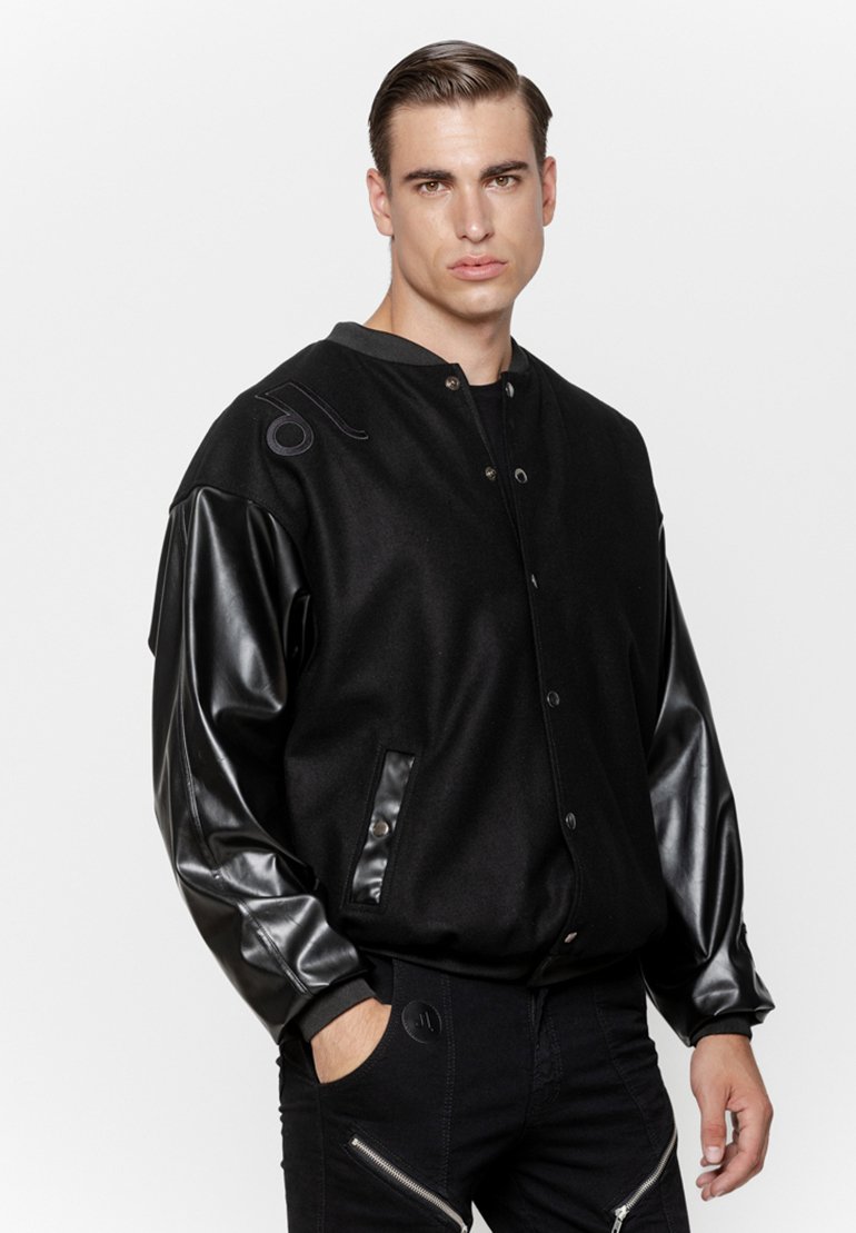 Czarna kurtka bombowiec z wełnianym korpusem i błyszczącymi czarnymi skórzanymi rękawami, z zatrzaskami i bocznymi kieszeniami, akcentowana minimalistycznym wzornictwem.