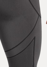 I leggings da palestra grigi presentano un tessuto liscio ed elastico con linee di accento nere e pannelli testurizzati per un dettaglio aggiuntivo.