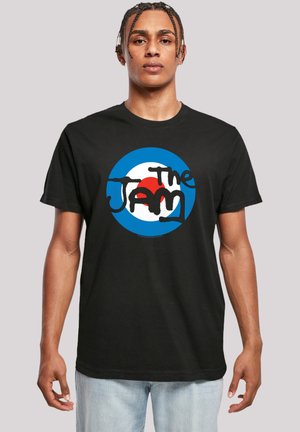 Black cotton t-shirt featuring a circular blue, white, and red graphic with bold text reading "The Jam" in a stylized black font.