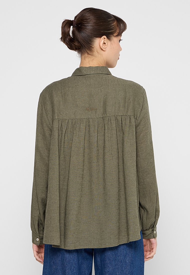 Chemise olive verte à manches longues avec un empiècement au dos et des plis. Fabriquée en tissu texturé avec des poignets à boutons. Détail du logo au dos visible.