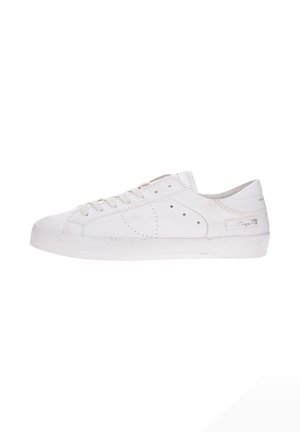 Zapatilla blanca de corte bajo con diseño de cordones, detalles perforados en los laterales y etiqueta "heritage 78" cerca del talón.