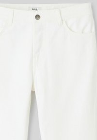 Pantalon en denim blanc avec une taille standard, fermeture à bouton et deux poches avant, présentant une texture lisse et un design épuré.