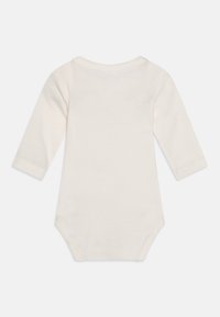 Body neonato a maniche lunghe in morbido cotone color crema. Presenta un collo rotondo e chiusure a pressione nella parte inferiore per facilitare il vestire.