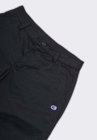 Pantaloni neri realizzati in un tessuto leggero e liscio. Presentano una chiusura con bottone e un piccolo logo ricamato in blu e rosso sulla tasca sinistra.