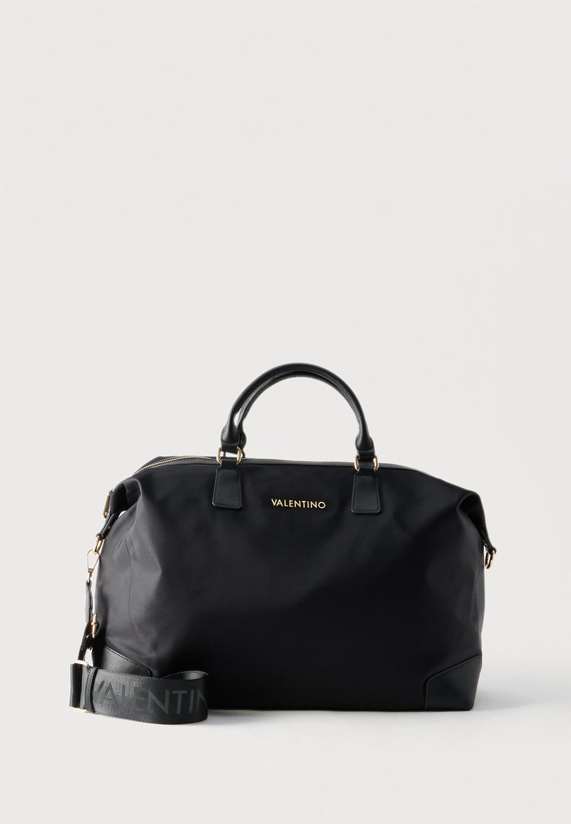 Μεγάλη μαύρη δερμάτινη τσάντα Valentino με διπλές λαβές και αποσπώμενο ιμάντα ώμου, χρυσό λογότυπο και εξαρτήματα, με λευκό φόντο.