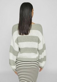 Gestreifter Pullover in Grau und Weiß mit horizontalen Streifen, lockeren langen Ärmeln und einem verkürzten Saum. Kombiniert mit einem schwarz-weiß gestreiften Rock.