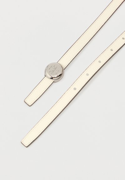 Kermainen nahkavyö hopeanvärisellä pyöreällä soljella, jossa on kohokuvioitu koristeellinen ristisymboli, kuvattuna auki valkoisella taustalla.