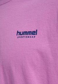 Lilla bomulds t-shirt med rund hals og korte ærmer. "hummel SPORTSWEAR" er trykt i mørkeblå på brystet.