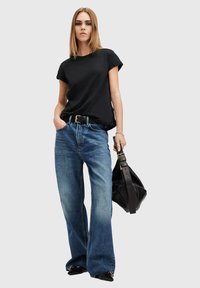 černé bavlněné tričko, volný střih; světle modré džíny s vysokým pasem a širokými nohavicemi; černá kožená taška se zlatými doplňky; tenký černý opasek.