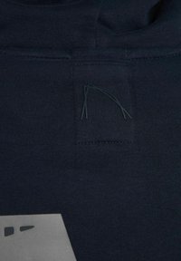 Tessuto di cotone blu navy con una texture sottile, caratterizzato da una toppa quadrata e da accenti scuri minimalisti in un design geometrico.