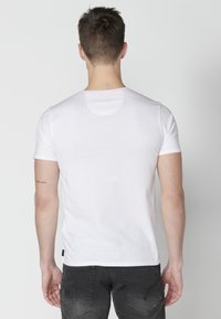 White cotton t-shirt with a round neckline and short sleeves, featuring a smooth texture and subtle stitching details.