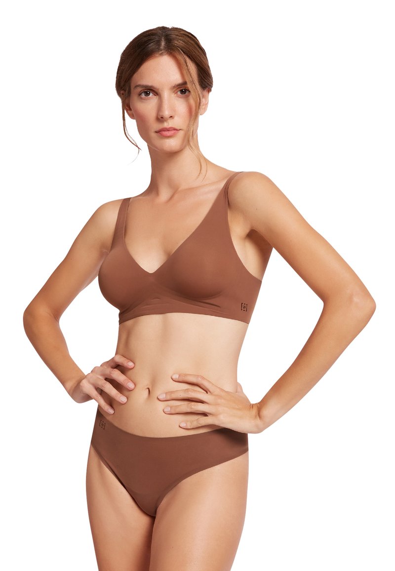 Set di reggiseno e panty seamless marrone con una texture liscia. Il reggiseno presenta spalline larghe e un design a V, mentre il bikini ha un taglio a vita bassa.