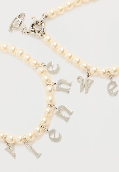 Βραχιόλια με χάντρες μαργαριταριού και ασημένια γράμματα που σχηματίζουν τη φράση "new wave" σε ανοιχτό φόντο, με ασημένιο κούμπωμα τύπου toggle.