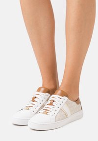 Sneakers bianchi con accenti in pelle, dotati di un pannello laterale in tessuto a motivi, punta tonda e suola piatta in gomma. Lacci marroni e dettaglio sul tab.