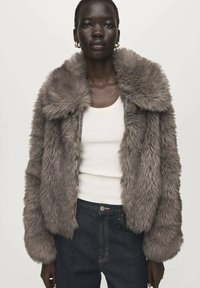 Graue Jacke aus Kunstpelz mit weitem Kragen, Reißverschluss und langen Ärmeln, getragen über einem weißen Tanktop und dunklen Jeans.