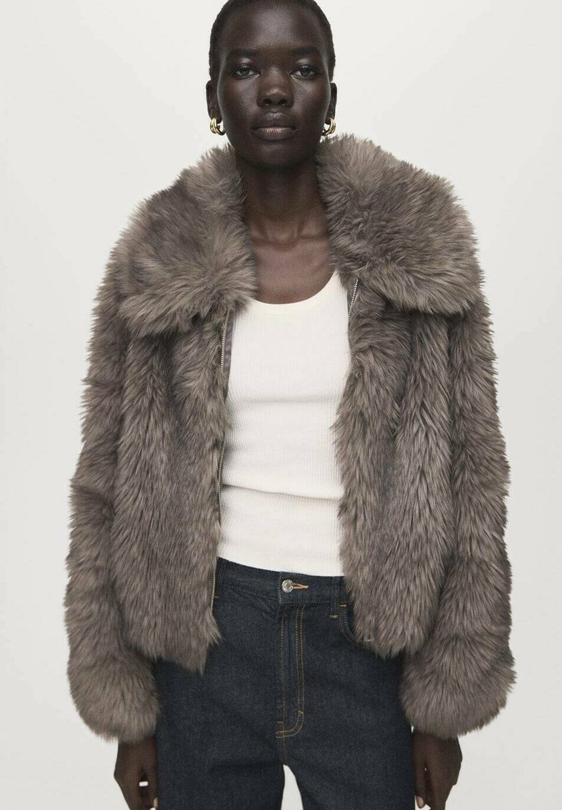 Graue Jacke aus Kunstpelz mit weitem Kragen, Reißverschluss und langen Ärmeln, getragen über einem weißen Tanktop und dunklen Jeans.