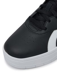 Juodas odinis sportinis batelis su apvaliu pirštu, tekstūruotu paviršiumi, balta šonine akcentu ir juodais raišteliais. Guma padukas su išgaubtu raštu.