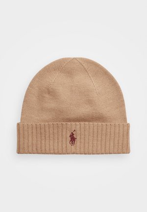 Bereta tricotată din material bej, cu o manșetă ribbed. Prezintă un mic logo maroniu cu un cal și un călăreț pe partea din față.