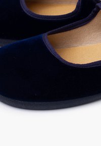 Bailarinas de terciopelo azul marino con puntera redondeada, ribete elástico y suela de goma negra texturizada. Plantilla de color beige suave visible en el interior.