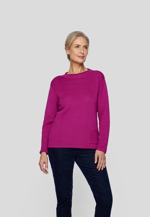 Magenta gestrickter Pullover mit horizontalen Streifen, Rundhalsausschnitt und langen Ärmeln. Kombiniert mit dunkelblauen Hosen, die über eine Seitentasche verfügen.