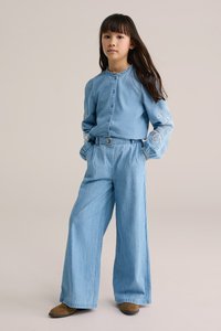 Sinine teksariidest särk ja laiad pidžaamapüksid, mõlemad heledas toonis. Särgil on dekoratiivne valge tikand varrukaosadel. Riietuse lõpetab pruuni värvi jalats.