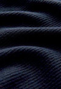 Ciemnoniebieska, teksturowana tkanina o delikatnym prążkowanym wzorze, prezentująca miękkie fałdy i różnice w świetle na powierzchni.