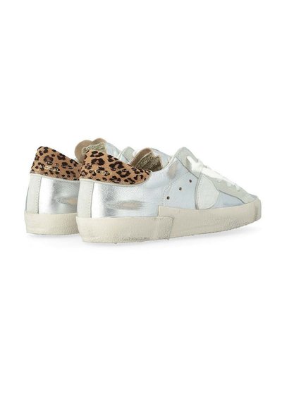 Zapatillas deportivas plateadas de caña baja con cordones blancos y suelas beige, con detalles de estampado de leopardo en el talón y perforaciones en los laterales.